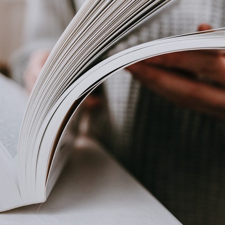 Lesungen & Vorträge Eine Person blättert durch ein offenes Buch mit einem hellen Hintergrund.